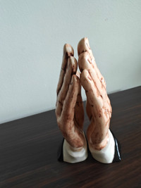 Ceramic sculpture of praying hands.