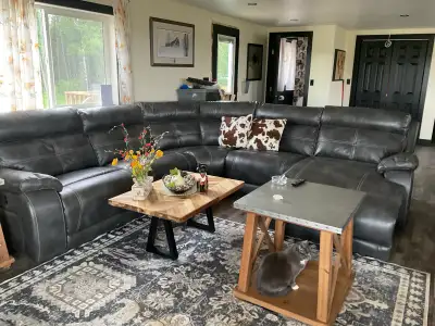 This is a large dark brown L-shaped sectional sofa with a chaise lounge on the right side, and with...