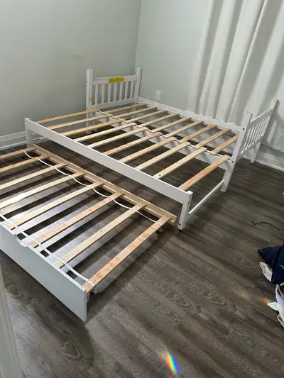 Barely used, white solid wood twin-sized bed which can be pulled out to form a king-sized bed with a...