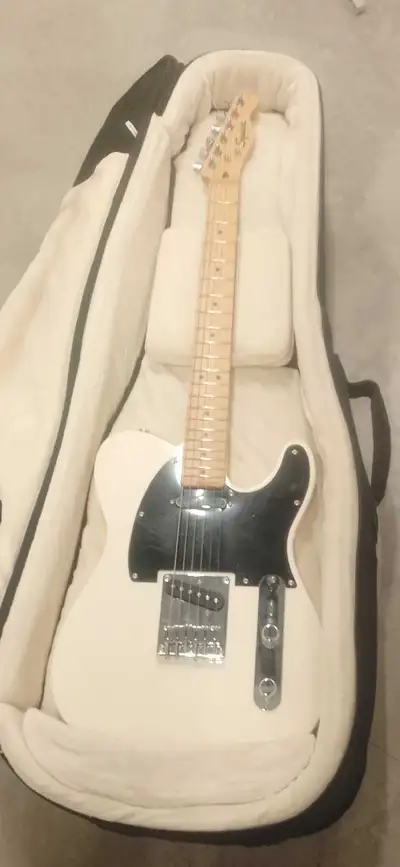 This pre-owned Squier by Fender Telecaster features a classic white finish with a black pickguard an...