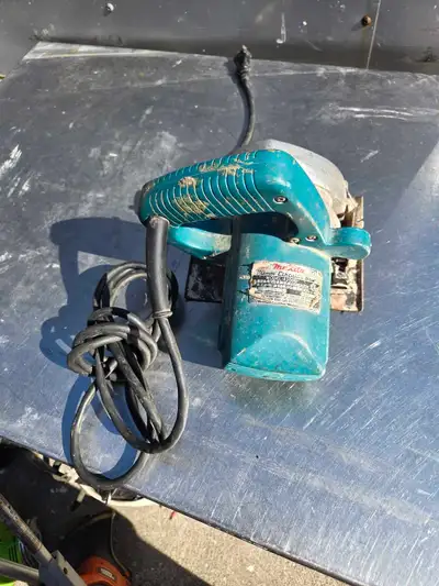 Used Makita 4200N circular saw is a corded power tool with a teal plastic body and a metal base. Thi...