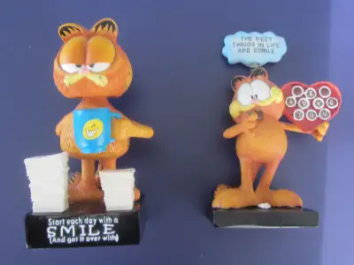 Two Garfield figures. The first is bobblehead with "Start each day with a SMILE (And get it over wit...