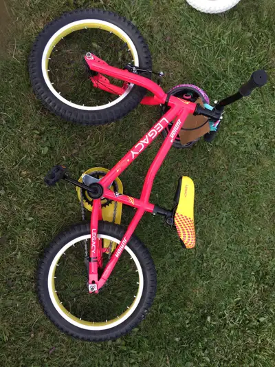 This is a Legacy Junior kids' bike with a vibrant pink frame and yellow accents, perfect for young r...