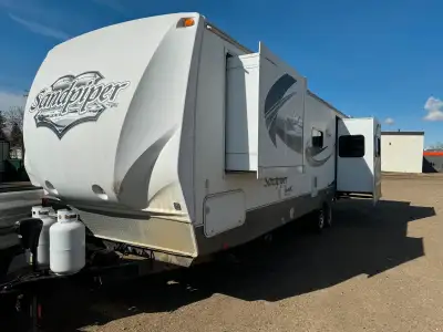 This is a Sandpiper fifth wheel, offering a comfortable and spacious living area with multiple slide...
