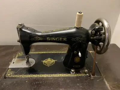 The Singer sewing machine is in working condition. The sewing machine is attached to a table as a se...