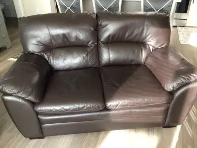Brown leather love seat with matching ottoman Like new condition open to offers must sell. MUST SELL...