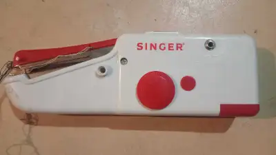 This is a used Singer handheld sewing machine, perfect for quick repairs and small sewing projects....