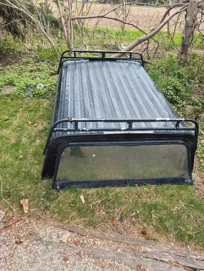 This is a black cap with a roof rack, designed to fit an older model pickup truck came off a 2009 Ra...
