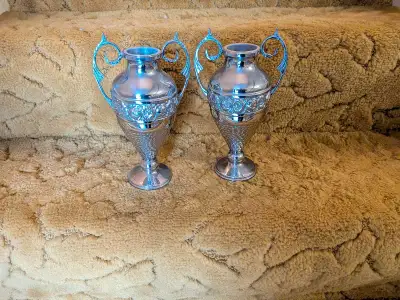 These elegant matching silver-plated decorative urn-style vases feature intricate relief detailing a...