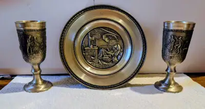 This German Pewter Collection includes a decorative plate and two goblets, showcasing intricate desi...