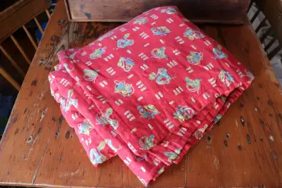 Vintage cowboy quilt. One side of the quilt is a red material that depicts cowboy themed items (hols...