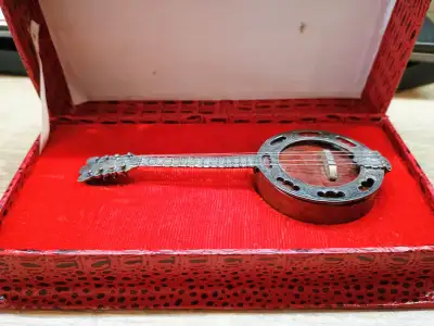 Miniature banjo 12.5 cm long comes with red case. I don't know if it is Sterling Silver or not. Cash...