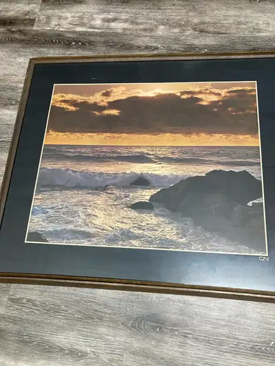 This pre-owned ocean sunset framed print captures a serene coastal scene with dramatic clouds and go...
