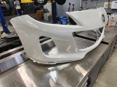 This is a white bumper from a 2012 Mazda 3. As you can see from the pictures it is damaged around th...