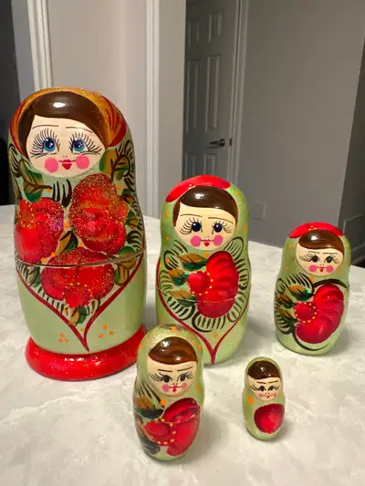 Hand-painted wooden Russian nesting doll (matryoshka) decorated with a light green background, a pai...