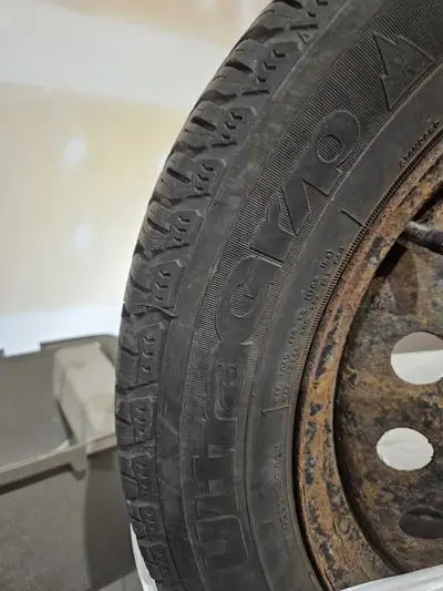 Set of four Goodyear UltraGrip winter tires, size 235/55R17, mounted on steel rims. These tires are...