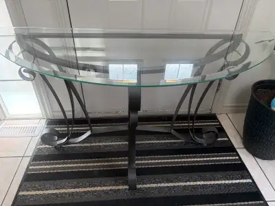 A half-moon shaped glass console table with a decorative metal base. This table's slim profile makes...