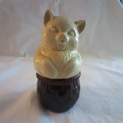 Sweet little cream colored kitty sits in a glass basket. Vintage Avon cream perfume bottle once held...