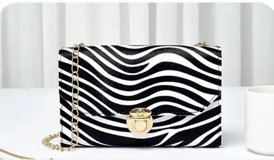 This is a chic zebra striped purse with a gold chain, perfect for adding a unique touch to your outf...