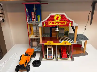 This vintage Fire Station comes with two cars and a tractor. This toy is in used condition, showing...