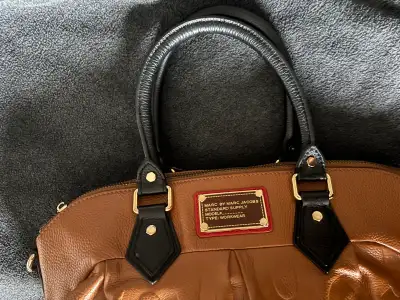 Très beau sac Marc by Marc Jacobs en cuir grainé cognac avec poignées noires contrastantes. Logo emb...