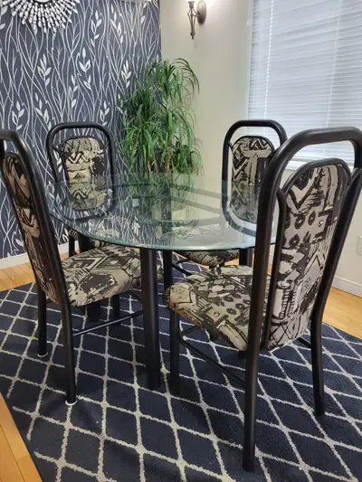 Glass dining table with 4 chairs. Some damages and strains in upholstery. Pictures included.