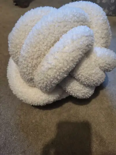 Add a touch of cozy charm to your living space with this plush white knot pillow! This decorative ac...