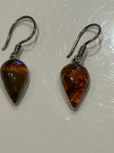 These are used amber and silver tear drop earrings. They feature genuine amber stones set in a sterl...