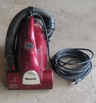 This is a pre-owned burgundy Shark handheld vacuum that's perfect for quick cleanups. It's in fair c...