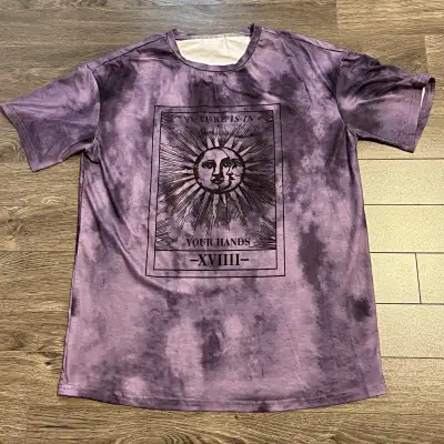 A cool purple tie-dye t-shirt featuring a tarot card graphic! The design includes a sun and moon fac...