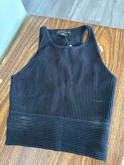 Black ribbed knit cropped tank top. Sleeveless with a round neckline.