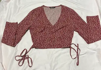 This is a cute, gently-used SHEIN top with a red floral pattern and wrap-around design, perfect for...