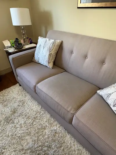 This contemporary 3-seat sofa features a clean, tufted-back design in a neutral light grey fabric th...