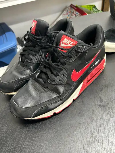 These are a pair of used Nike Air Max 90s in black and red, size 11 US. The shoes have been worn, sh...