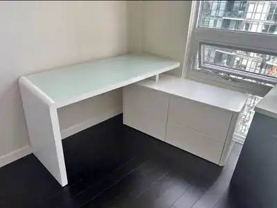 Modern white office desk with a thick glass work surface, integrated storage cabinet and drawers. Go...