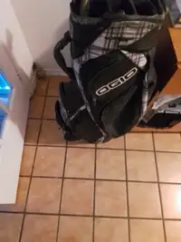 Golf bag with some right and irons and a few drivers umbrella  