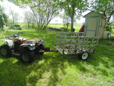 Homemade narrow utility trailer used for collecting firewood along narrow paths on woodlot. The deck...