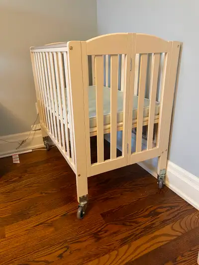 Like new amazing condition mini portable foldable baby crib in off white colour on wheel frame with...