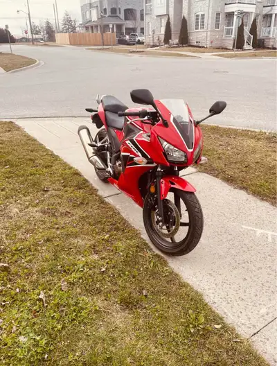 Clean motorcycle in red with black accents. Has a sporty look and appears well-maintained. Exhaust p...
