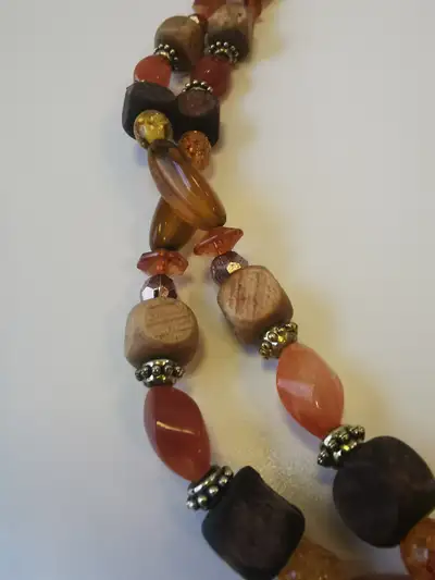 This is a long 28-inch beaded necklace made of amber-colored wooden beads in a round shape. It does...