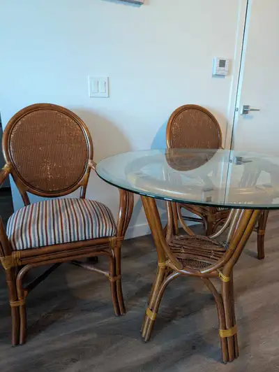 This is a used rattan table with two chairs, perfect for a cozy breakfast nook or small dining area....