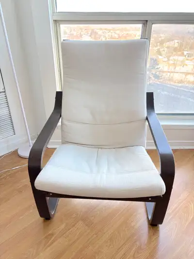 This is an IKEA POÄNG rocking chair with a brown frame and light beige cushion The bentwood frame pr...
