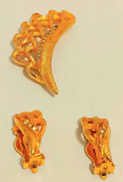 This is a used vintage jewellery set that includes a decorative pin and clip-on earrings, featuring...