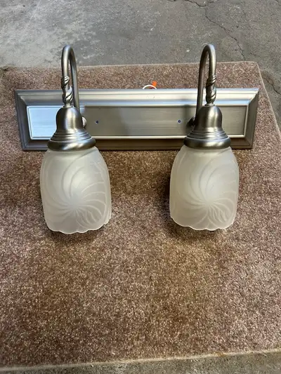 Brushed chrome vanity light fixture with two frosted glass covers. 18" wide x 4.5" high. Mounting pl...