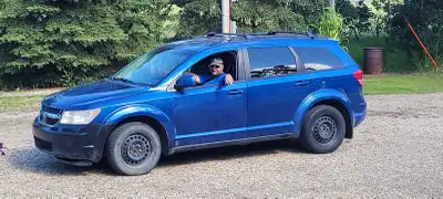 This is a blue Dodge Journey, a versatile SUV perfect for families or anyone needing extra space. It...