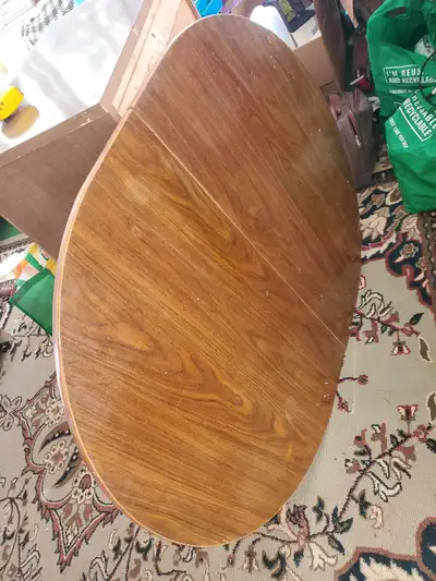 This is a used kitchen table with a rounded, extendable leaf design, perfect for a cozy dining space...