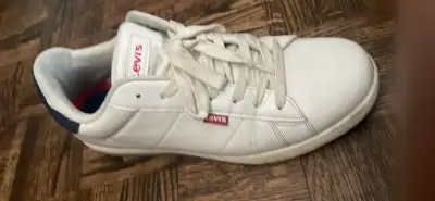 White Levi's sneaker has red branding on tongue and side. Shoe has white laces and blue insole with...