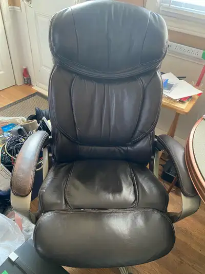 This is a used, brown leather office chair designed for comfort during long work hours, featuring a...