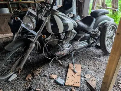 This Yamaha V Star features a classic cruiser design with a distinctive black and white striped fuel...