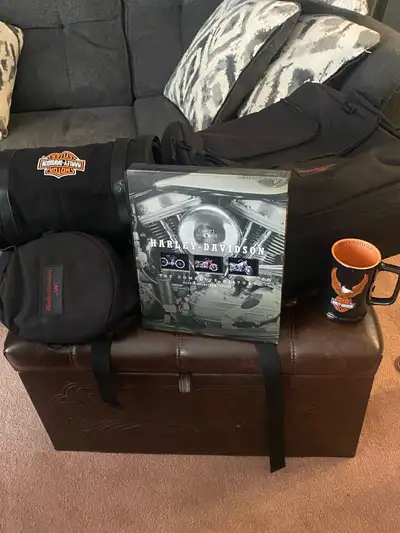 Three pieces of Harley Davidson luggage and the ultimate coffee table book, and a Stein/mug celebrat...